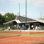 Het clubhuis gezien vanaf de tennisbanen, met zicht op het zij-terras,